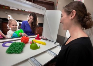 Heidi Tomik, daughter of Christiane Conn Tomik '03, associate director of alumni relations, selects an object in response to a question from Renee Gallo ’14, right, as Rachel LeWitt ’13 watches.