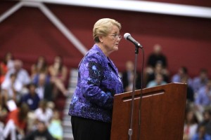 Peggy Lawson shares stories about her husband's life from the podium in the Kirby Sports Center arena while others listen.