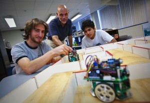 Professor John Greco with two students and a moving electronic device