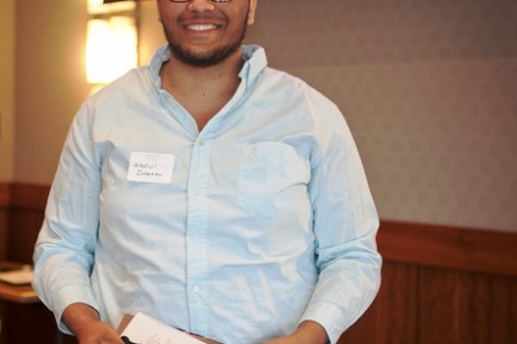 Abdul Dopson ’14 receives a senior gift and ribbons to wear with his robe at Commencement.