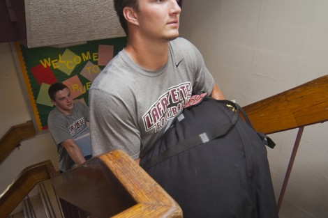 Football player Michael Root ’18 carries a first-year student’s gear into Ruef Hall.