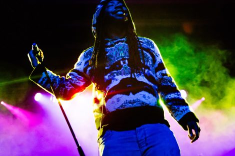 Rapper DRAM holds the microphone as colored lights set the background.