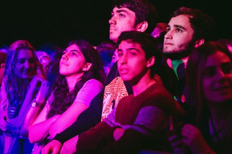 Four students look at the performers on stage at the Spring Concert.