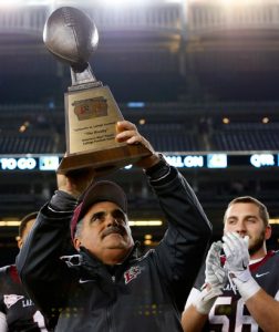 Football coach Frank Tavani holds the trophy for winning the 150th Lafayette-Lehigh football game.