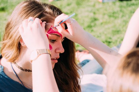 A student paints another students forehead.