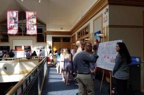 Professor Chris Ruebeck discusses two students' research poster with them.