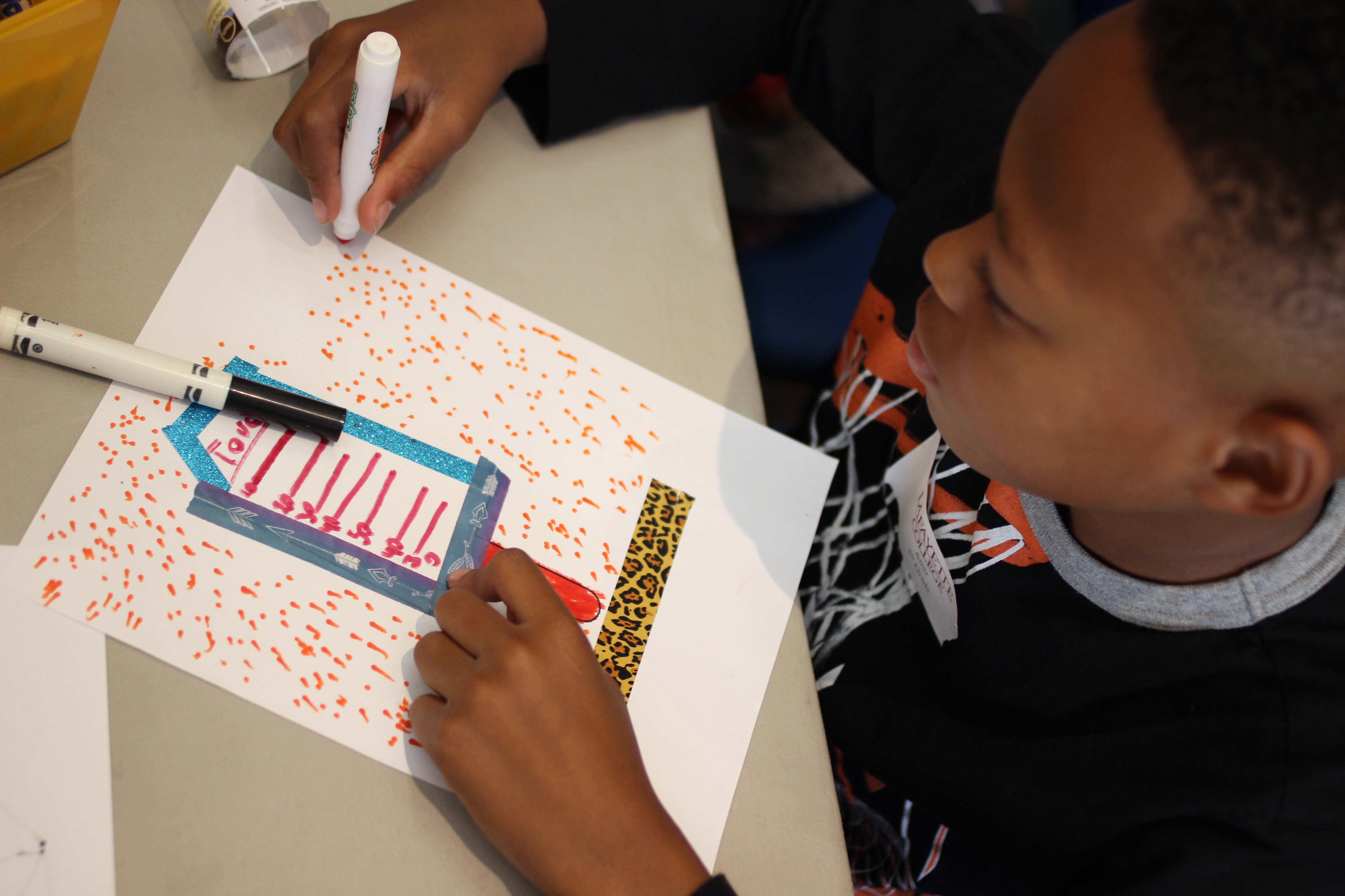 A male child draws with a magic marker.
