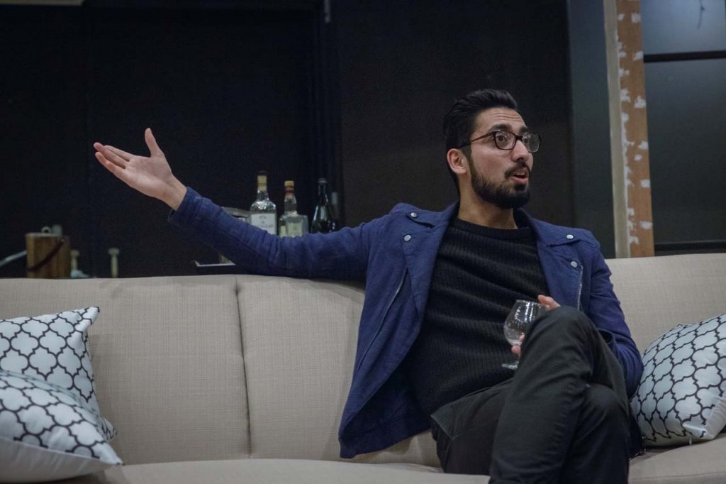 An actor in the play Disgraced talks while sitting on a couch.