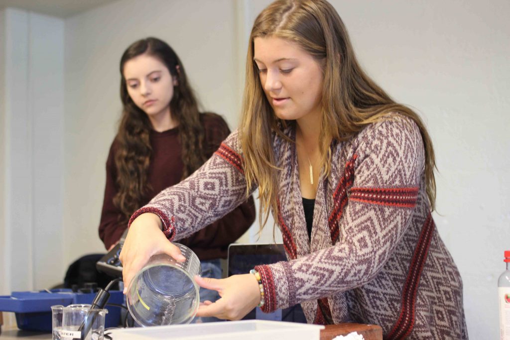 A Lafayette woman student pours liquid from a beaker.