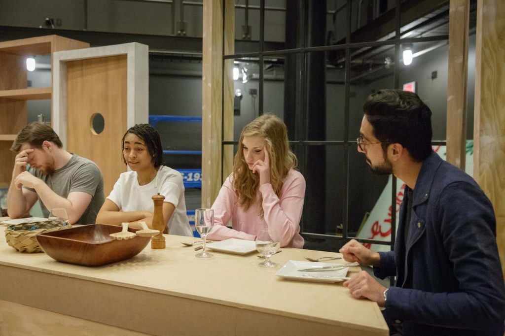 Actors rehearsing the play Disgraced sit together at a table.