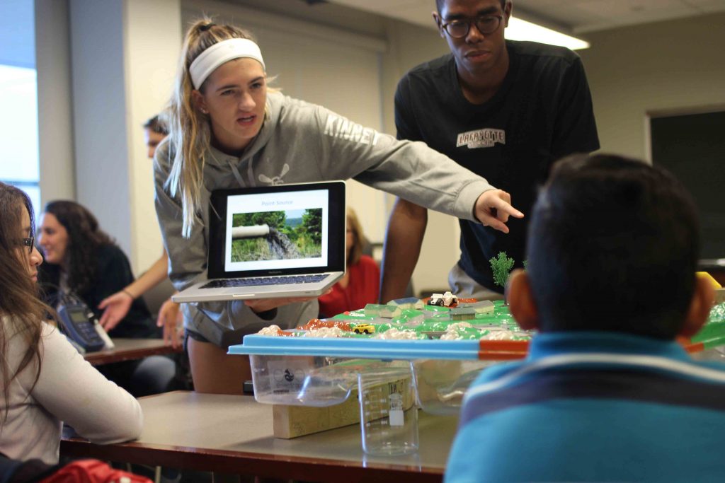 A woman Lafayette student points to the pollution model as she teaches.