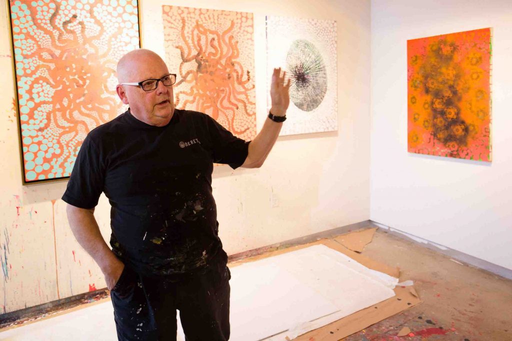 Ed Kerns talks in front of a few of his paintings.