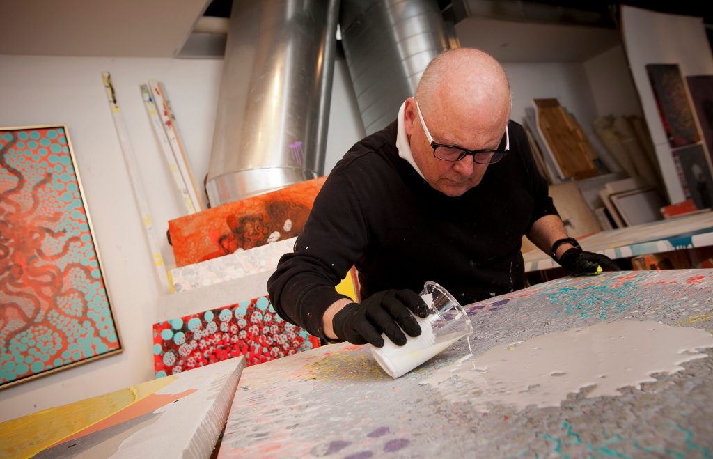 Ed Kerns pours liquid on one of his paintings.