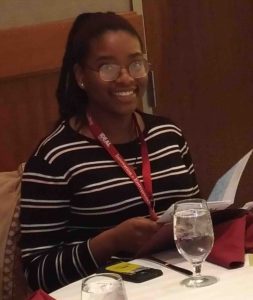 A female student smiles at the dinner table.