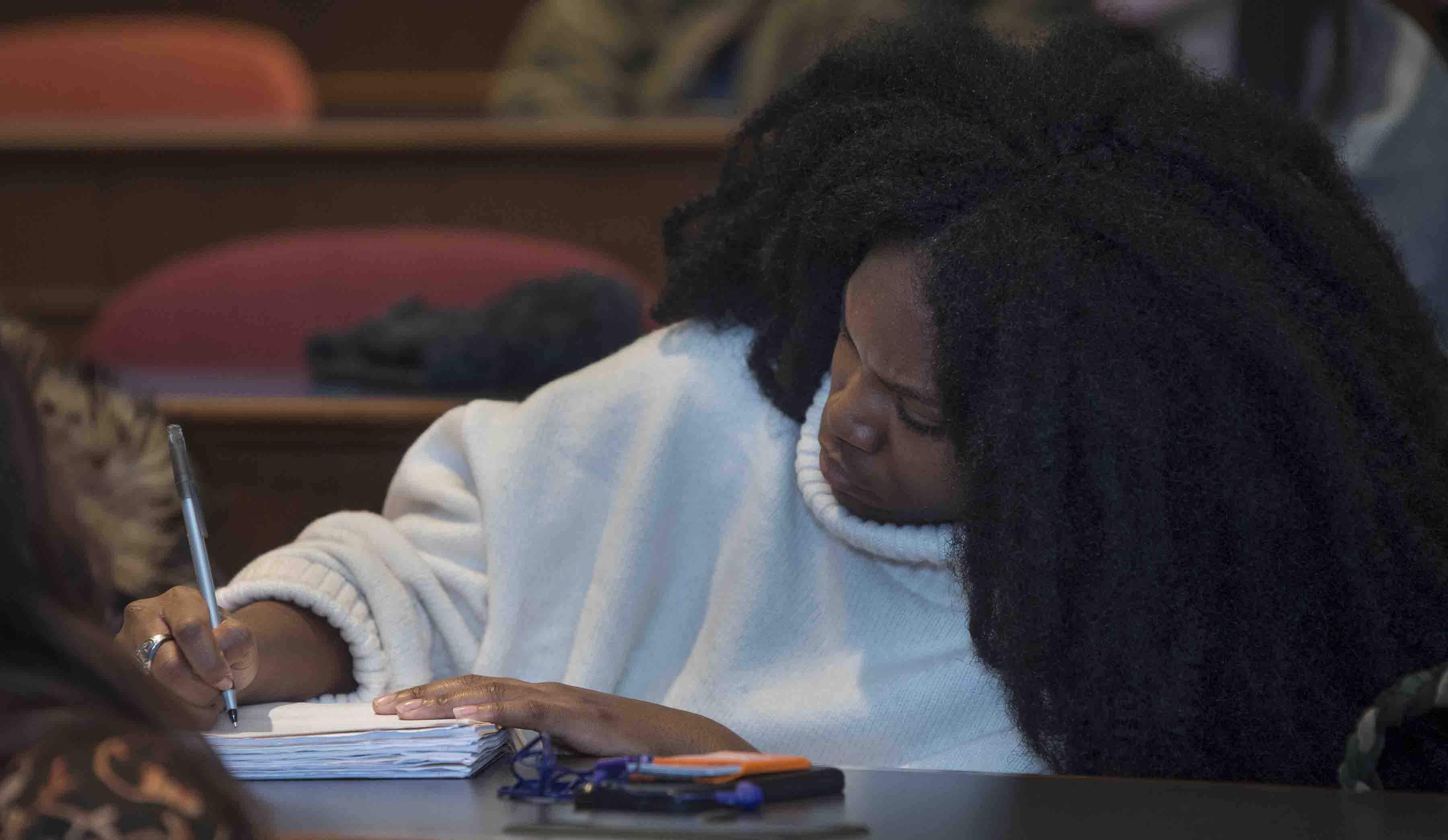 A student takes notes on Kevin Young's lecture on fake news.