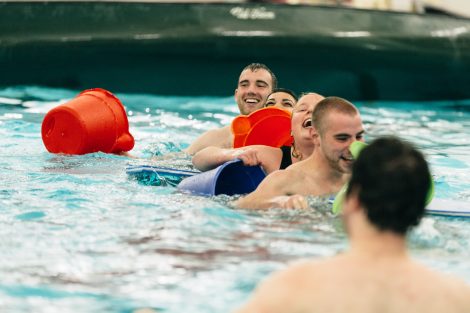Students try to flood and sink other canoes in the Battleship game in Weinstein Natatorium.