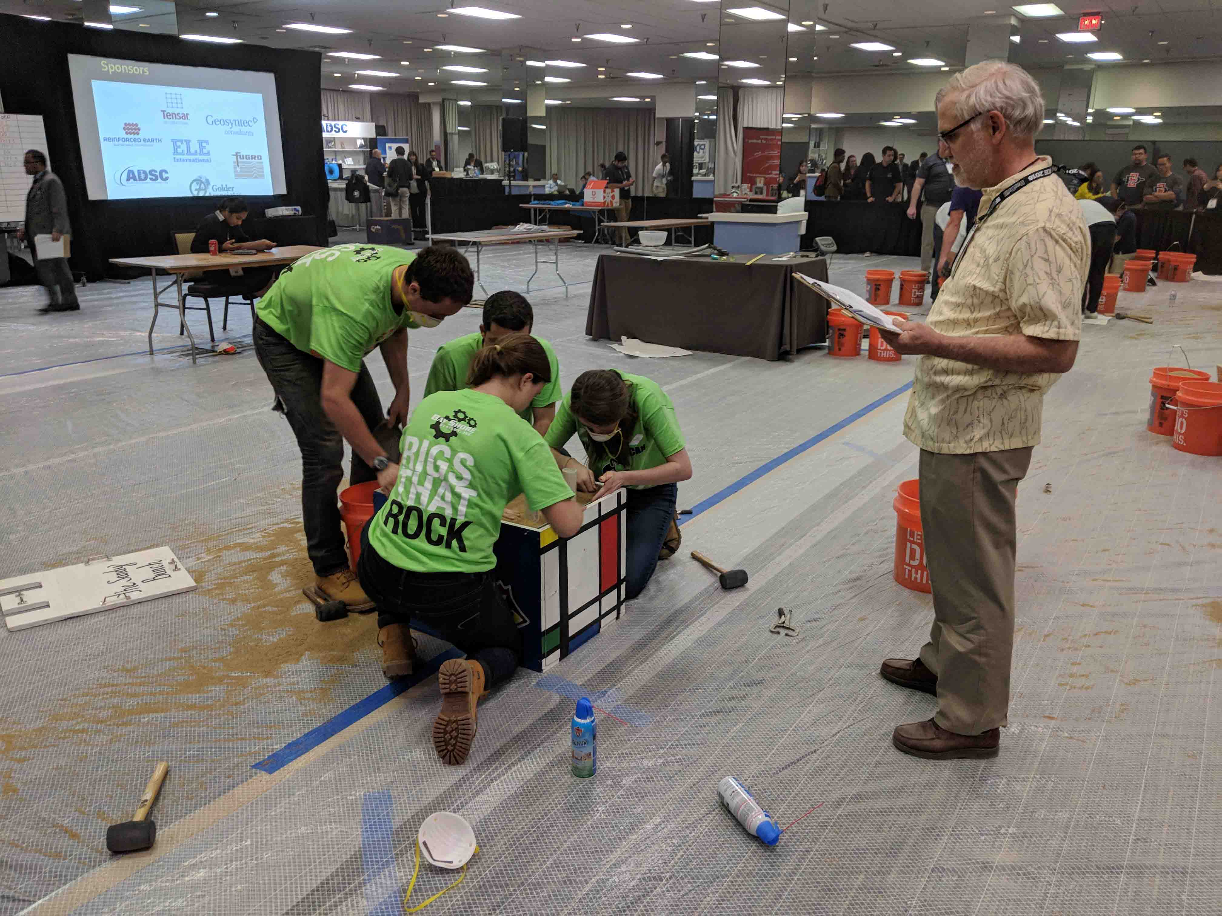 Lafayette students assemble a project in the Geotechnical Engineering Competition as a judge watches.
