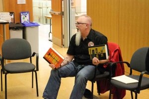 Cosmic Cup and Two Rivers Brewing owner Troy Reynard holds two books while talking about entrepreneurship