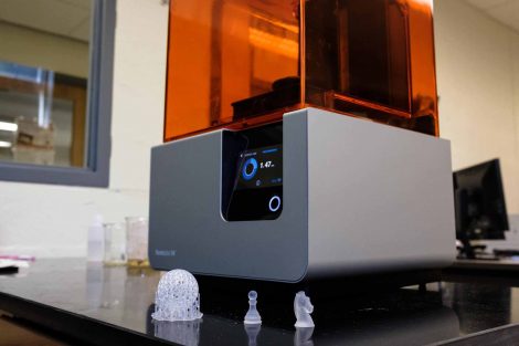 3D printer and three items created with it, including pawn and knight chess pieces