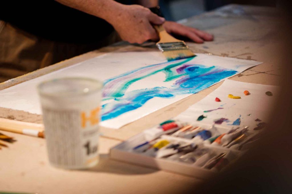 Ed Kerns paints on a piece of paper.
