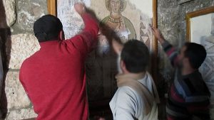 Men appear to be scratching off a Western religious painting.