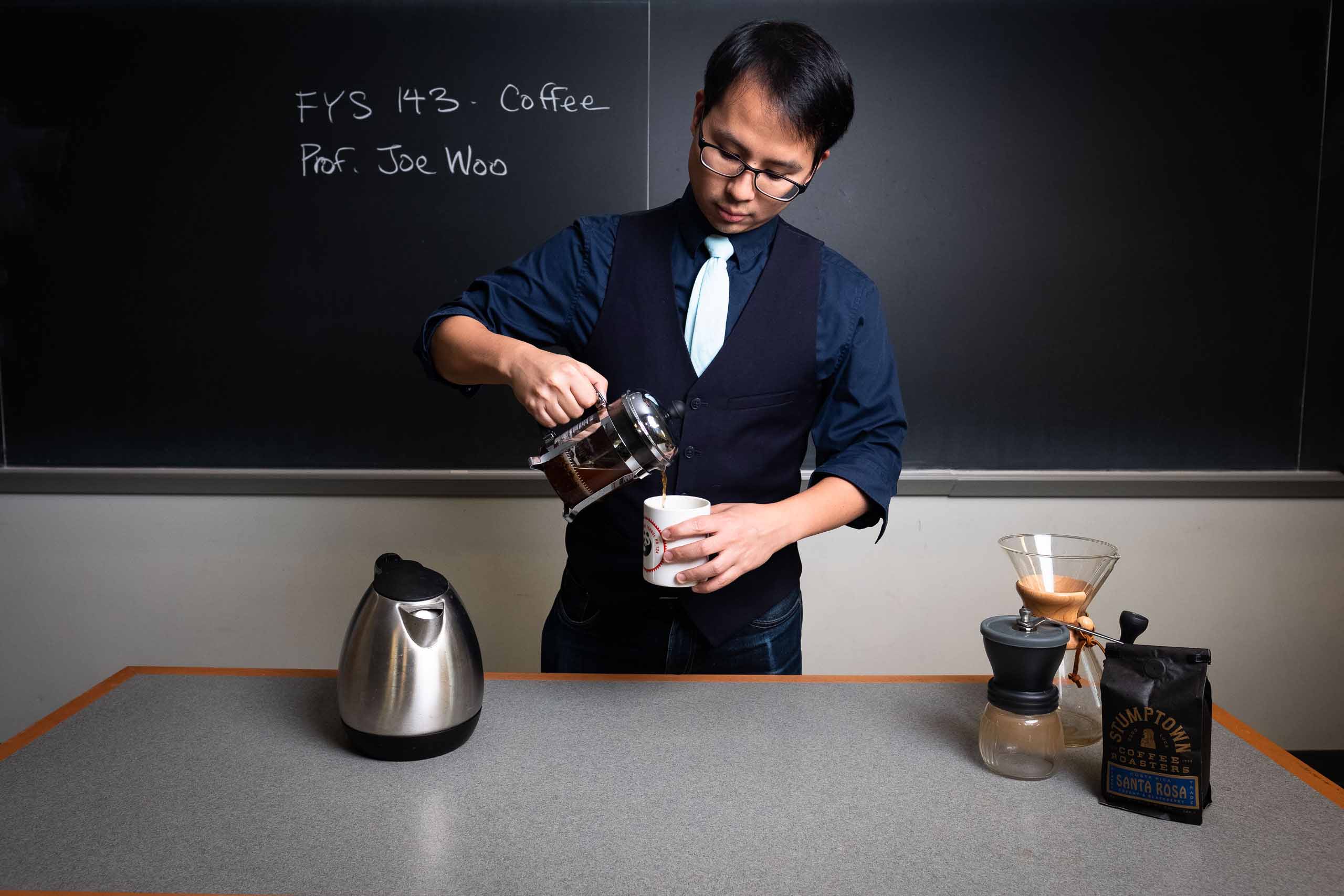Professor Joe Woo pours a cup of coffee in his classroom.