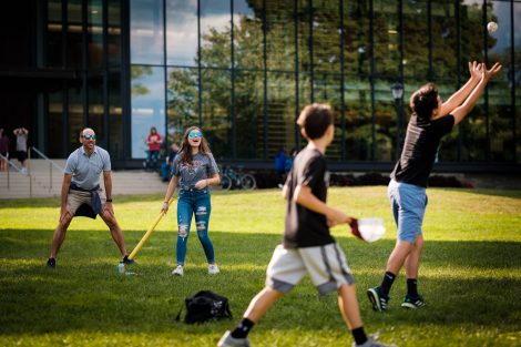A family plays whiffleball on the Quad.