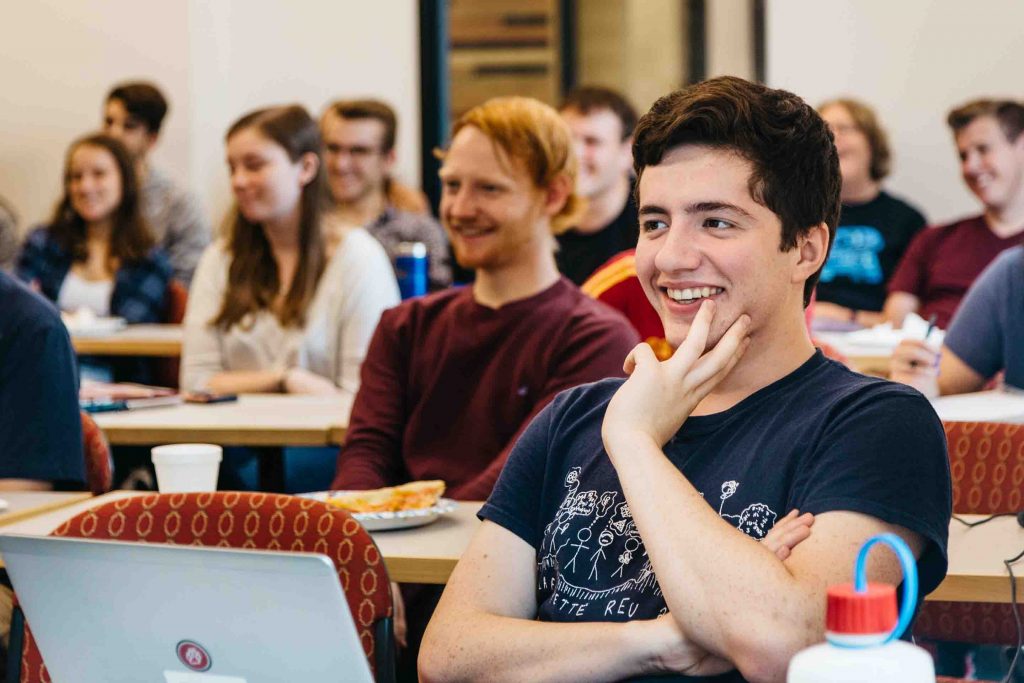 A student smiles as he listens to one of the math alumni.