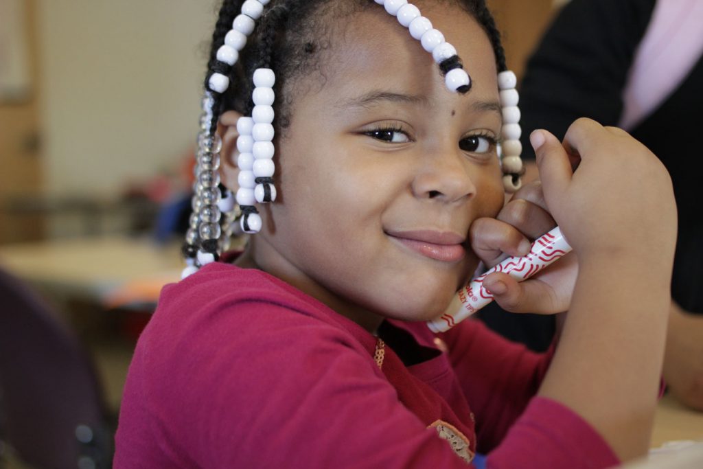 A girl smiles and holds a magic marker at Boys and Girls Club of Easton.