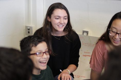 Lafayette students from the First-Year Seminar Happiness class laugh with school children.