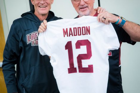 Chicago Cubs manager Joe Maddon '76 holds a football jersey with his name on it while Lafayette football coach John Garrett stands with him.
