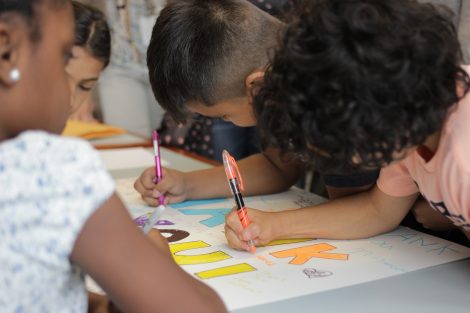 Local third-graders use markers to create letters on a poster during a class taught by Lafayette College students in the Happiness First-Year Seminar.