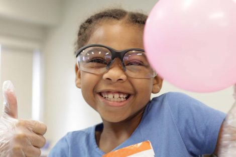 Girl smiles with pink balloon.