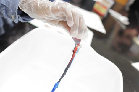 Student adds food coloring to beaker.