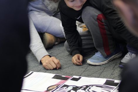 Elementary students put puzzle pieces together that they colored.