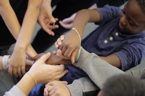 Elementary students get their wrists rubber banded together.