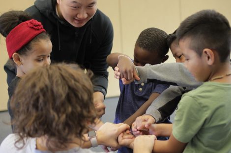 Lafayette student helps rubber band elementary student wrists.