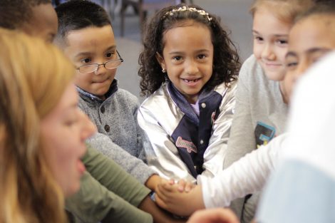 Elementary students smile with wrists rubber banded.
