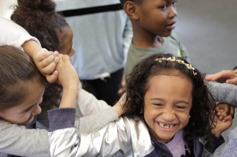 Elementary students laugh as they get untangled.