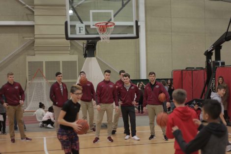 Fifth graders take turns shoot baskets with Lafayette athletes.