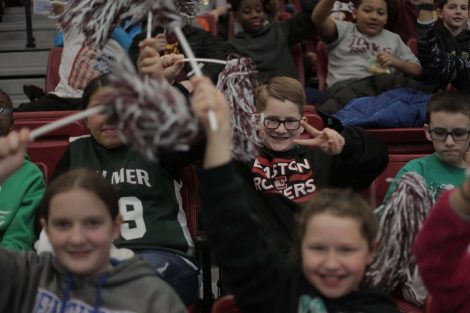 Boy flashes peace sign as he cheers.