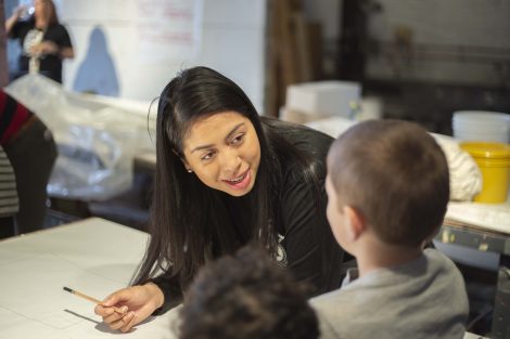A Lafayette student helps kindergartners with their pencil drawings.