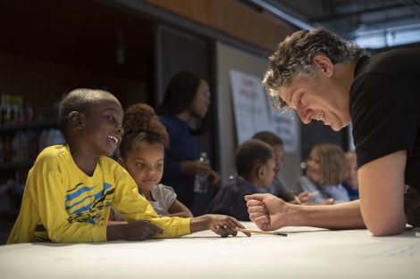 Nestor Gil smiles while working with a student on his drawing.