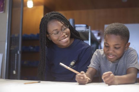 A Lafayette student helps a young child with his pencil drawing.