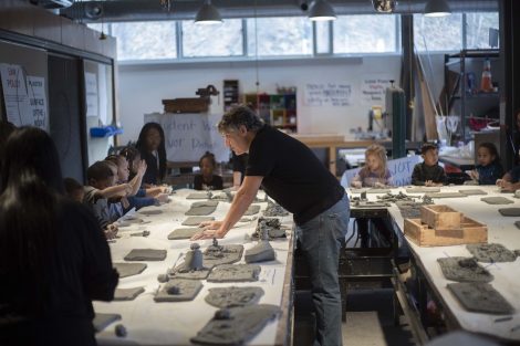 Nestor Gil leans over the table looking at the clay work.