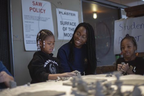 A Lafayette student watches a kindergartner work with clay.