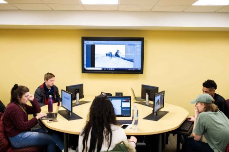 Students in the workshop share their work on a TV screen.