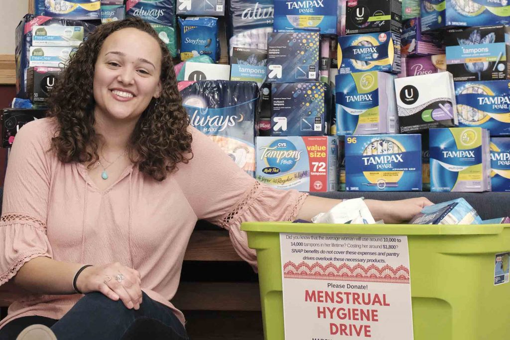 Jazmyn Ball ‘20 sits in front of stacks and stacks of menstruation products collected in a month-long drive.