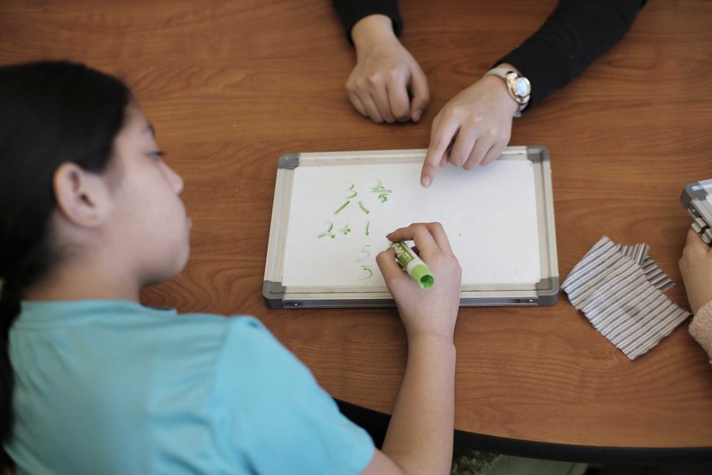 Close up of student's hands as she explains fraction subtraction.