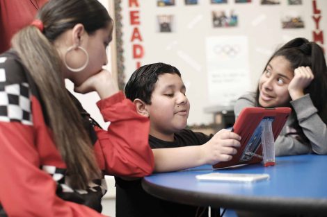 Third grader shows his sisters his code projects.